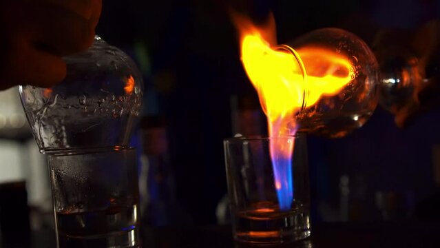 The barman prepares a set of sambuca cocktails on the bar counter.