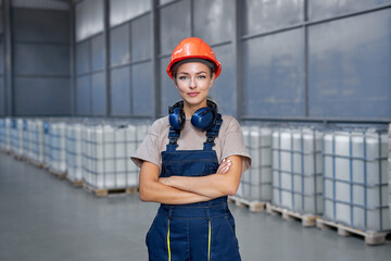 industrial woman engineer in hardhat standing in factory with arms folded, posing, wearing uniform,...