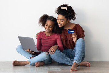 Happy black mother and daughter shopping online together, closeup