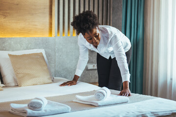 Housekeeper cleaning a hotel room. African housekeeper in a hotel room. Maid making bed in hotel...