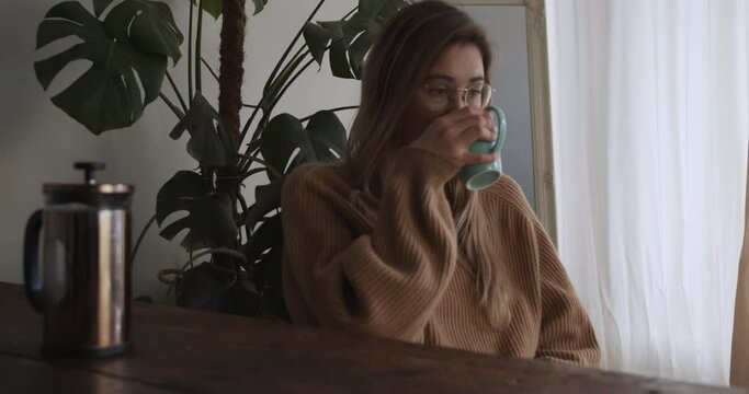 Girl takes her coffee cup in the morning and looks out of the window