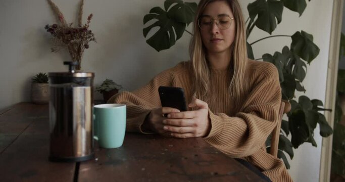 Girl textes on her smartphone while having her coffee