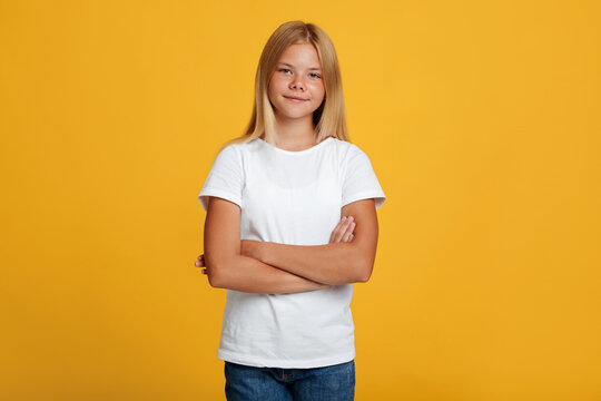 Serious confident teenager blonde girl in white t-shirt crossed arms on chest, look at camera