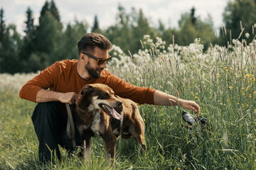 Caucasian man and two dogs in tall grass in rural.