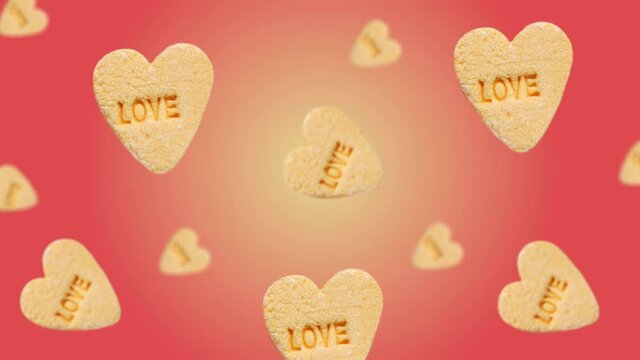 Flying and wiggle of different diameters heart-shaped yellow candies with label "Love"  on trending red color gradient background. Romantic Love concept for mother's, St. Valentine's and women's day.