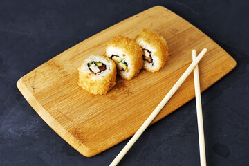 sushi and rolls on a wooden board with wasabi sticks and ginger