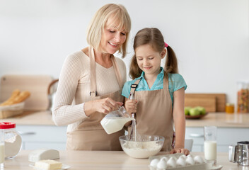 Obraz na płótnie Canvas Happy senior lady and her granddaughter kneading dough
