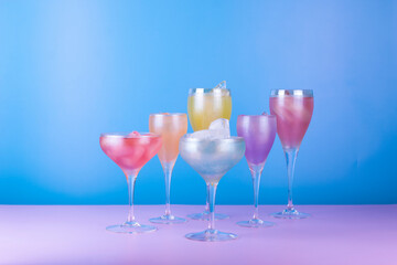 Various cocktail glasses with colorful drink on blue and pink background. Cocktail party concept