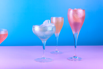 Various cocktail glasses with colorful drink on blue and pink background. Cocktail party concept