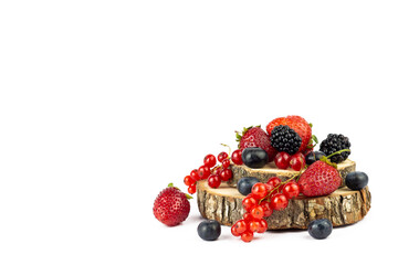 Round wooden stand with ripe mixed assortment berries on white background. Summer or Spring Organic...