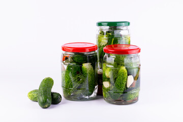Pickled cucumbers in  glass jar with fresh cucumbers  on white background.