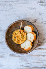 Bread baguette with homemade hummus in an old clay plate on a wooden table. A plant-based, healthy, vitamin-rich, balanced vegan food. Dish with red onion, pepper, dill and olive oil. Middle East.