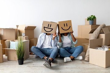 Moving and real estate concept. Black couple with cardboard boxes with smiley faces on head,...
