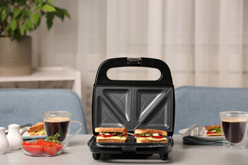 Modern grill maker with sandwiches and coffee on light grey table indoors - obrazy, fototapety, plakaty