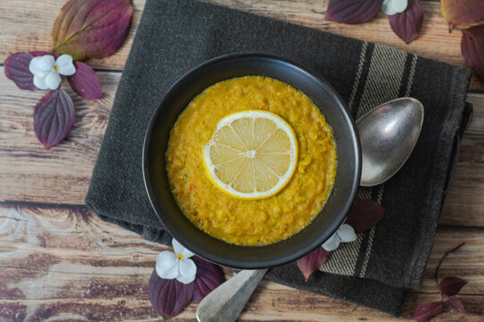 Bol de soupe de lentilles corail surmont&eacute;e d'une tranche de citron