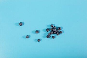 Little heap of blueberry on blue background. Flatlay of blueberries with copy space.
