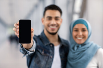 Beat App. Cheerful Islamic Couple Showing Smartphone With Black Screen At Camera