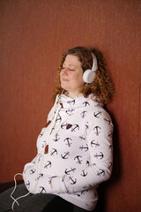 Frau in Sweater mit weissen Kopfhörern geniesst Musik