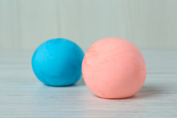 Different color play dough balls on white wooden table, closeup