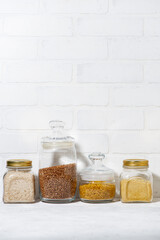 assortment of cereals in glass jars on a white background, vertical