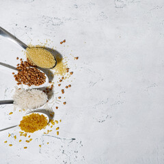 assortment of cereals in spoons on a white background, vertical top view