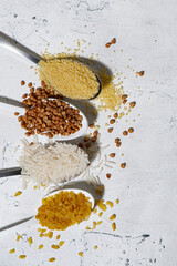 assortment of cereals in spoons on a white background, vertical