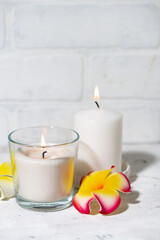 white burning candles and flowers on a white background, vertical closeup