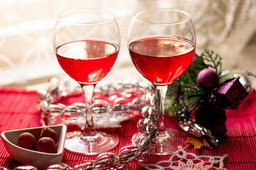 close-up of two glasses of red wine on a festive New Year's table against a light curtain