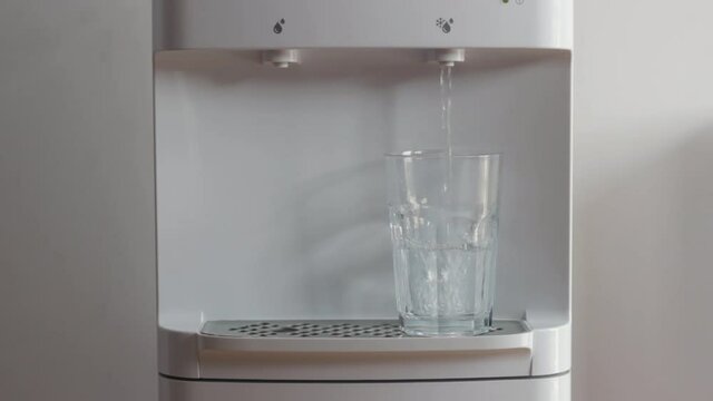 Man is taking a glass of cold water from the water dispenser. Clean water for healty lifesyle.