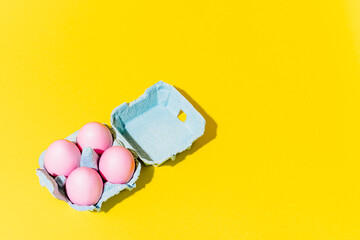 An egg cup with pink eggs on a yellow background