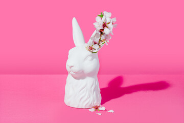 Bust of a white rabbit with almond blossoms on a pink background