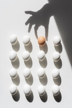 Easter white eggs pattern On A White Background With Shadows. One is brown and different from the others