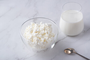 Bowl with fresh cottage cheese and a glass of milk on table. Space for text
