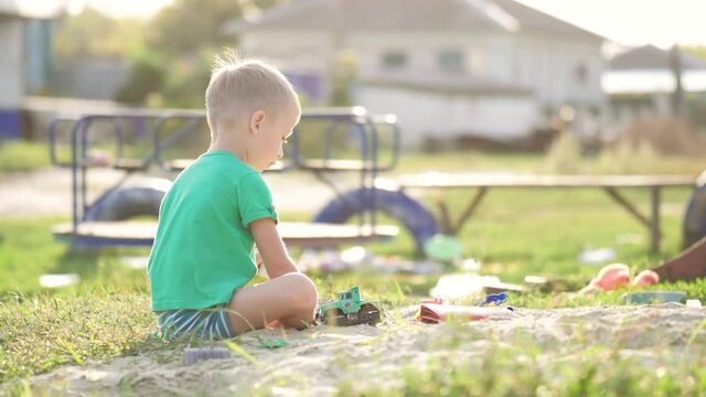 Boy plays sand toys outdoors. Little sweet boy playing in sandbox on playground. Child playing in the sandbox with toy. Happy family healthy children concept.