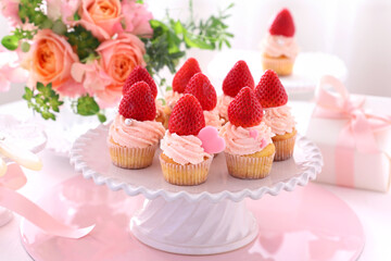 Valentine cupcakes with white chocolate and strawberry cream with strawberry. 
Valentine bouquet of rose flowers  and gift.