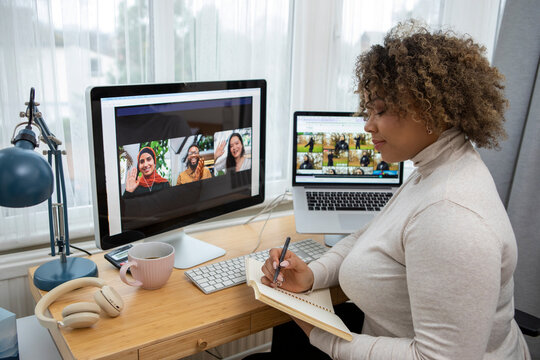 Woman making notes during video conference at home