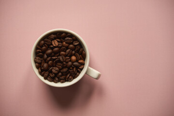 ziarna kawy w białej filiżance na różowym tle