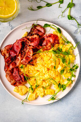 Traditional breakfast scrambled eggs with fried bacon