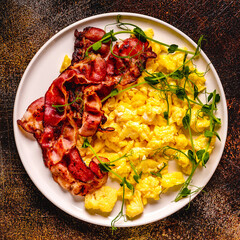 Traditional breakfast scrambled eggs with fried bacon