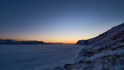 Sunset, view from the bank of the frozen river.