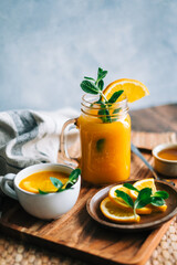 Sea buckthorn tea in a glass with fresh orange, mint and honey on table.