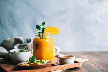 Sea buckthorn tea in a glass with fresh orange, mint and honey on table. copy space