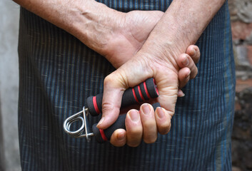 Asian, Myanmar old man gripping hand exercise gripper.