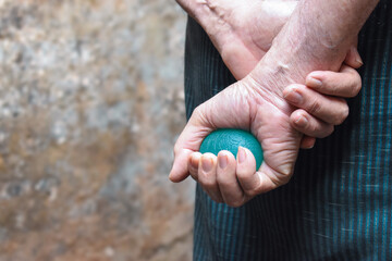  Asian elder man gripping hand exercise elastic ball.
