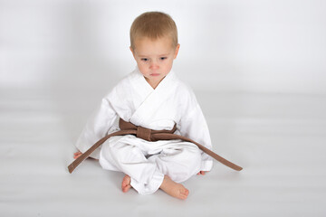 Little baby boy in karate kimono isolated on white background. The concept of martial arts, karate,...
