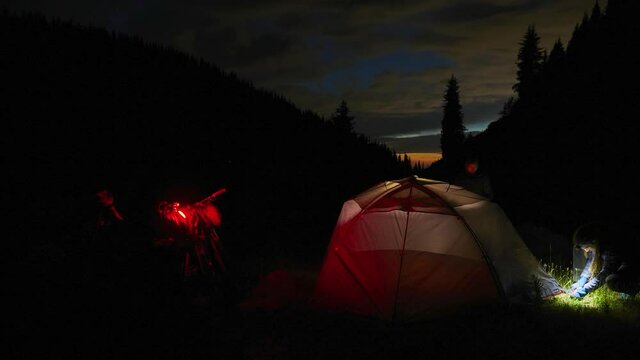 Tourist setup Orange iluminated tent in the forest under the starry sky