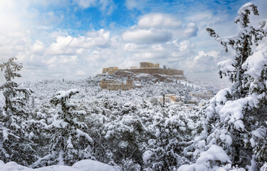 The Parthenon Temple at the Acropolis of Athens, Greece, with thick snow and blue sky during winter time