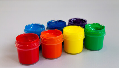 Open cans of paint of different colors stand in a row. Palette, gouache and acrylic paints for creativity, close-up.