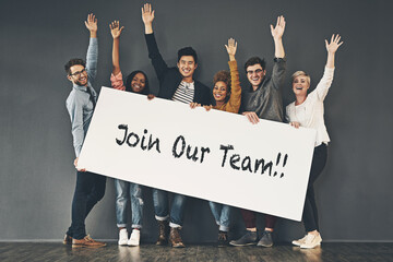Come and join our team. Studio shot of a diverse group of people holding up a placard against a...