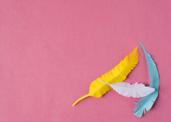 paper feathers on vibrant pink background with copy space